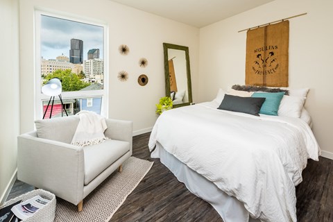 a bedroom with a bed and a chair and a window